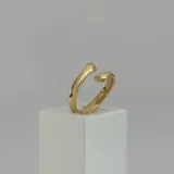 Anillo dorado con diseño de manos abrazándose.