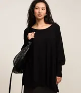 Suéter de tricot negro con mangas murciélago, escote canoa y puños ajustados.
