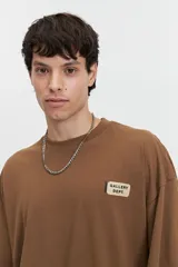 Remera marrón de manga corta con calce holgado y logo estampado en el pecho.