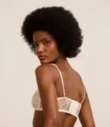 Soutien sin copa con aro, confeccionado en encaje floral color blanco. Presenta tirantes finos regulables y removibles, y cierre trasero con gancho.