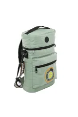 Mochila cilíndrica acolchada color gris, diseñada para transportar un equipo de mate (matero). Presenta un compartimento principal superior con cierre, un bolsillo frontal con cierre y un parche circular con texto y logo de Discovery. Incluye asa de mano superior y correa ajustable para llevar al hombro.