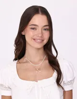 Collar corto doble, con cadena superior de perlas y cadena inferior dorada con dije de moño.