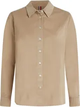 Camisa de manga larga color beige de pana con cuello clásico, cierre frontal con botones, logo de Tommy Hilfiger en la muñeca y detalles distintivos de la marca.