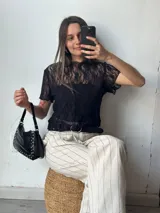 Remera de encaje negra con mangas cortas y cuello redondo. Incluye top interior liso.