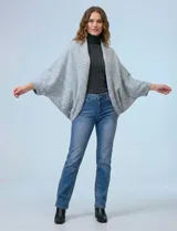 Cardigan negro de tejido suave, estilo poncho o capa, con cuello tipo chal y mangas amplias.
