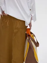 Falda midi de denim color marrón con hilado a la vista en el ruedo y abotonadura frontal.