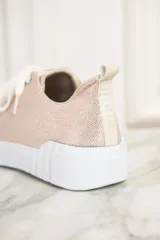 Zapatillas color arena metalizado con cordones blancos y suela blanca con estrías horizontales.