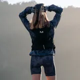 Campera cortaviento gris con estampado camuflado, cierre frontal completo, capucha ajustable y logo de la marca en el pecho.