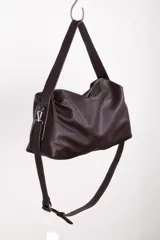 Bolso tipo hobo color borgoña, de cuero con textura granulada. Tiene correa de hombro ajustable y extraíble, cierre superior con cremallera, forro interior de algodón con bolsillo con cremallera y bolsillo abierto.