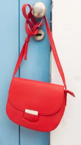 Bandolera pequeña de símil cuero color azul marino, con tapa curva y cierre metálico rectangular plateado. Incluye correa ajustable fina.