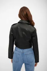 Campera estilo biker corta, color negro, confeccionada en cuerina (poliuretano) con forro de poliéster. Presenta solapas con broches, cierre asimétrico plateado, bolsillos con cierres y un cinturón con hebilla en el ruedo inferior.