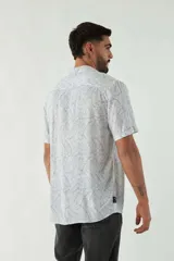 Camisa celeste con estampado de hojas, de corte slim, manga corta, cartera abotonada y logo bordado.