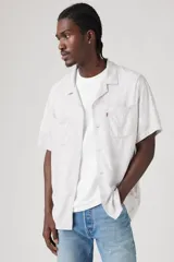 Camisa de manga corta con estampado abstracto en tonos grises y blancos, cuello tipo camp y cierre frontal con botones.