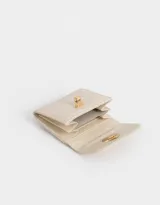 Billetera pequeña color crema con textura croco, solapa con broche dorado en forma de corazón y múltiples compartimentos para tarjetas y billetes.