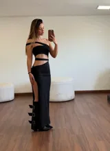 Vestido largo negro con aberturas en la cintura y en la pierna, con tiras finas y hebillas decorativas en la parte inferior.