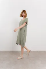 Vestido corto color verde oliva, confeccionado en lino, con corte recto y mangas cortas. Presenta bolsillos laterales y botones decorativos en los laterales.