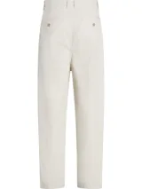 Pantalón cropped holgado color crema, confeccionado en sarga de algodón regenerativo. Presenta cintura plisada, cierre mediante botón y cremallera, bolsillos de hendidura y bolsillos traseros ribeteados.