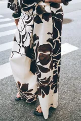Pantalón de tiro alto con delantero cruzado y broche, con estampado floral en tonos marrones sobre fondo crudo.