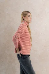 Polera de punto a rayas horizontales color celeste y blanco, de cuello alto y mangas largas.