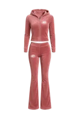 Conjunto deportivo de terciopelo color rosa, compuesto por un hoodie corto con cierre y un pantalón acampanado. Ambos con logo estampado en blanco.