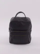 Mochila negra de cuero con cierre superior y tres bolsillos externos con cierre. En el interior tiene un bolsillo con cierre, un bolsillo abierto para celular y un llavero. Tiene una tira en la parte trasera para sujetar al carry on.