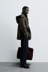 Parka verde oscuro confeccionada en tejido con lana, corte regular, cuello solapa con capucha desmontable, manga larga con puño ajustable, bolsillos de vivo en cadera y cierre frontal con cremallera oculta por solapa con botones a presión.