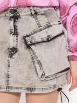 Minifalda gris con efecto lavado, bolsillos cargo laterales con solapa y cordones ajustables en el ruedo.