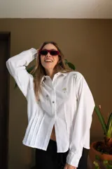 Camisa blanca de lino con bordados dorados de árboles, corte recto, cuello camisero y mangas largas con puños abotonados.