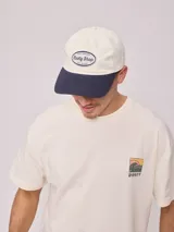 Gorra de lona lavada color azul con visera curva y parche bordado con el logo de Rusty en el frente.
