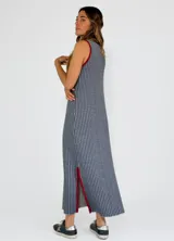 Vestido largo a rayas verticales color gris y blanco, con cuello en V y ribete amarillo. Presenta aberturas laterales con ribete amarillo.