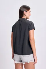 Camiseta tipo polo negra de manga corta con cuello clásico y botonadura parcial.