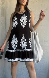 Vestido corto negro con estampado de flores blancas, corte recto y ruedo con volados.