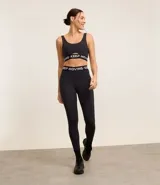 Top deportivo negro de microfibra con breteles anchos, copas desmontables, recorte cut-out en el busto y banda elástica con estampado de letras "Keep Moving".