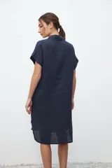 Vestido camisero azul marino de lino, corte recto, largo a la rodilla, con cuello clásico, manga corta y abotonadura frontal.