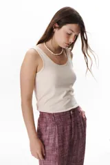 Musculosa color beige claro, con cuello redondo y tirantes anchos. Presenta un detalle de collareta metalizada en el escote.