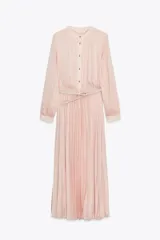 Vestido midi color rosa pálido, de cuello redondo y manga larga. Tiene cintura elástica, detalle de cinturón y cierre frontal con botones.