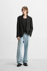Blazer negro de corte regular fit, confeccionado en tejido con viscosa. Presenta cuello con solapas de muesca, manga larga con puños abotonados, bolsillo de vivo en el pecho, bolsillos de solapa en la cadera, bolsillo interior, aberturas en la espalda y cierre frontal con dos botones.