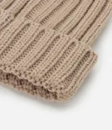 Gorro de lana color blanco con textura acanalada y pompón de pelo sintético en la parte superior.
