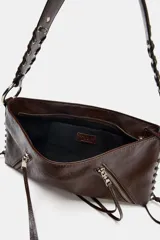 Bolso de hombro color gris topo, con formato rectangular y asa corta. Presenta dos bolsillos frontales con cierre de cremallera y detalle de tiras colgantes. El asa es de cuero trenzado con herrajes metálicos.