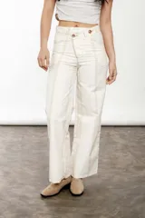 Pantalón wide leg de lino y algodón color crudo con rayas verticales finas color rosa. Tiene tiro medio, cartera cruzada con botones carey y bolsillos laterales.