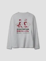 Camiseta gris de manga larga con cuello redondo y puños ajustados. Estampado en la espalda con dos personas cargando una tabla de surf y texto en inglés y japonés. Logo de la marca en la manga izquierda.