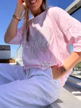 Remera rosa de mangas cortas con un corazón de lentejuelas y la palabra 'Happiness' escrita en blanco.