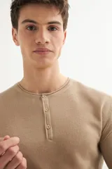Sweater de acrílico color beige, de manga larga y cuello redondo con botones.