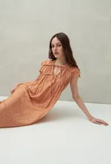 Vestido largo lila con escote con lazo, mangas cortas y frunces en el pecho.