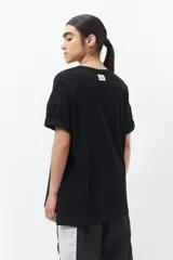 Remera oversized de algodón color beige, con manga corta, cuello a la base y botones en los laterales.