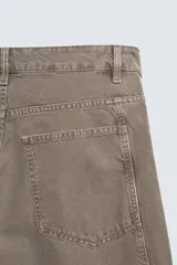 Pantalón de jean color marrón topo, de corte holgado y amplio en toda la pierna, con tiro medio, cinco bolsillos, efecto lavado, detalle de pinzas en perneras y cierre frontal con cremallera y botón.