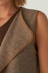 Chaleco marrón con solapas amplias y terminaciones envivadas. Diseño reversible y sin mangas.