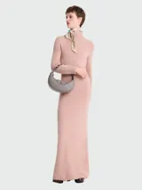 Bolso bandolera pequeño de cuero color gris con forma de media luna, cierre superior con cremallera y botón a presión, correa de cuero ajustable y extraíble, y herrajes plateados.