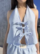 Top celeste a rayas verticales blancas, con escote halter y múltiples lazos frontales.