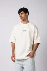 Remera color crema de corte oversize con la palabra "Rewind" bordada en el frente.